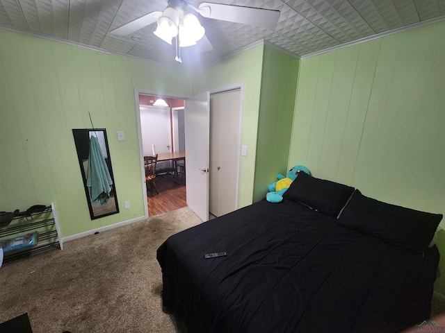 bedroom with carpet flooring, ceiling fan, wood walls, and ornamental molding