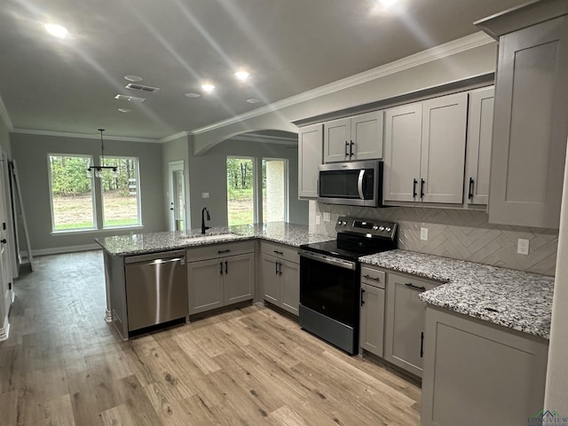 kitchen featuring decorative backsplash, ornamental molding, light stone counters, kitchen peninsula, and stainless steel appliances