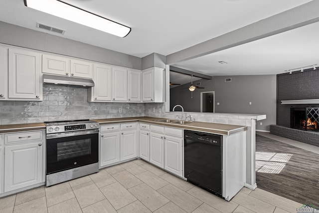 kitchen featuring white cabinets, black dishwasher, a fireplace, sink, and stainless steel range with electric stovetop