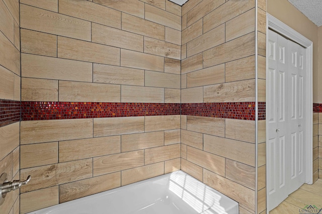 bathroom featuring a textured ceiling and a bath