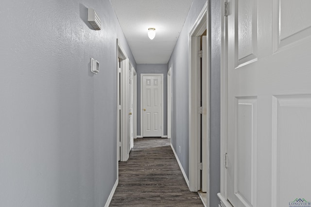 hall with a textured ceiling and dark wood-type flooring