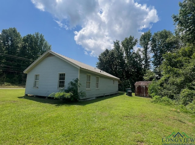 view of side of property with a yard and a shed