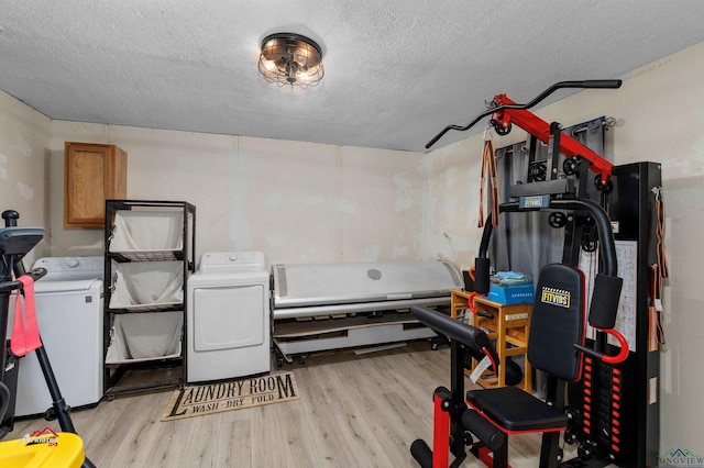 workout room featuring separate washer and dryer, a textured ceiling, and light wood-type flooring