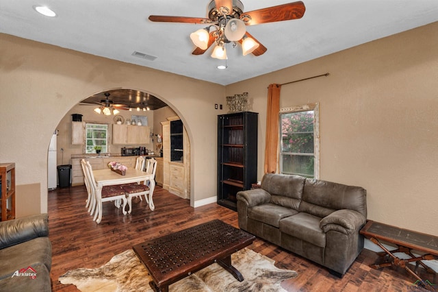 living room with ceiling fan and dark wood-type flooring