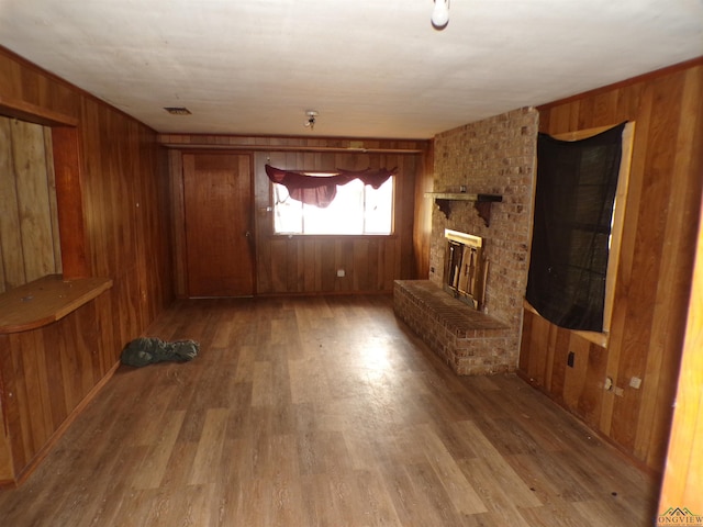 unfurnished living room featuring a fireplace, hardwood / wood-style floors, and wood walls