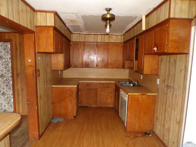 kitchen with stainless steel dishwasher, light hardwood / wood-style floors, crown molding, and sink