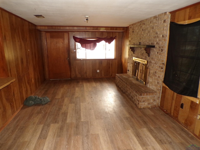 unfurnished living room featuring a fireplace and wooden walls