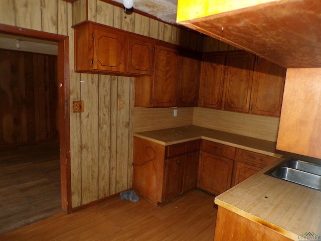 kitchen with wooden walls, sink, and hardwood / wood-style flooring