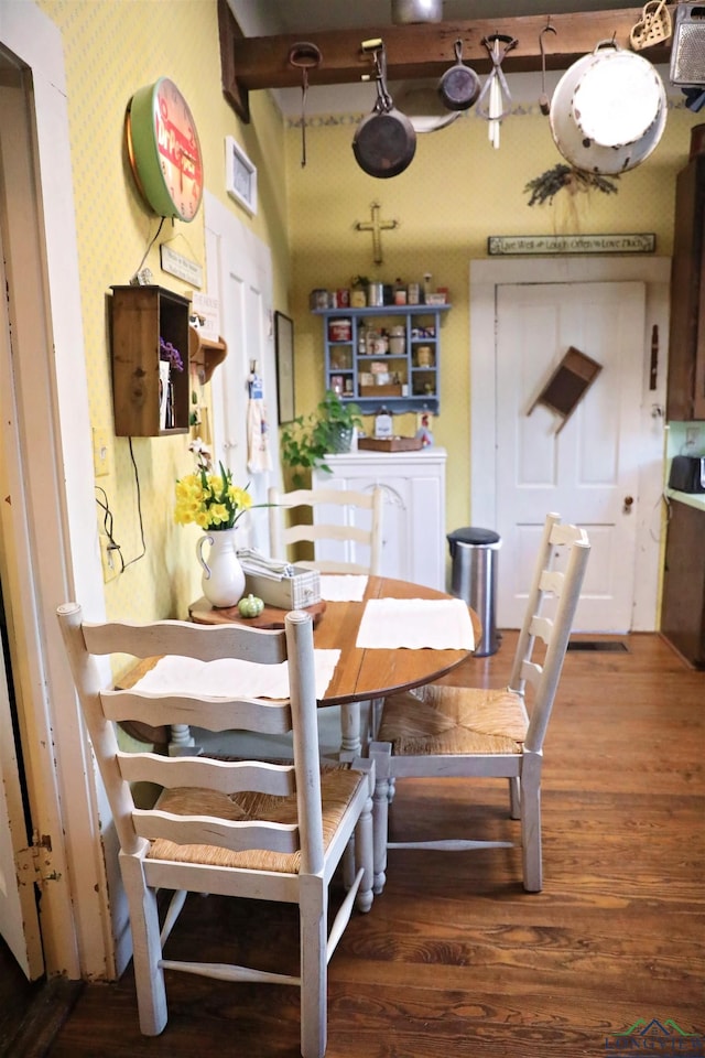 dining area featuring beamed ceiling and dark wood-type flooring