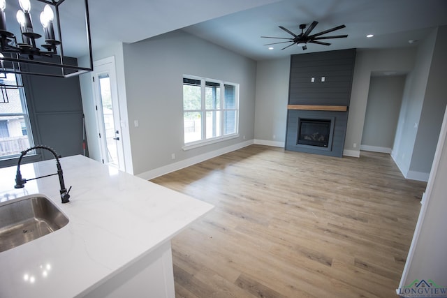 kitchen featuring light stone counters, sink, a fireplace, and a wealth of natural light