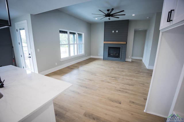 living room with ceiling fan, a fireplace, and light wood-type flooring