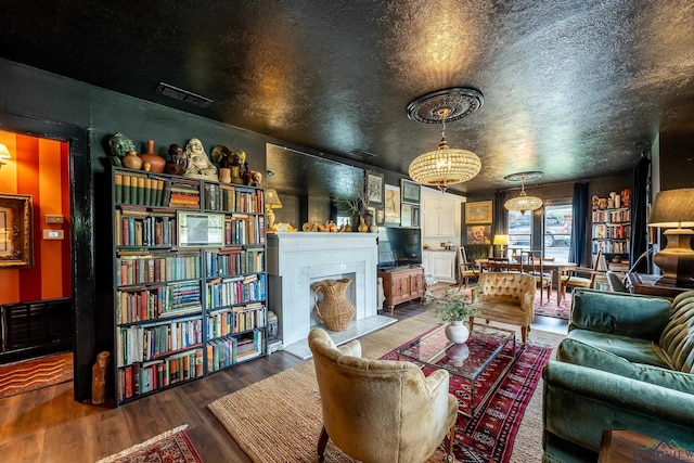 living room with wood-type flooring, a textured ceiling, and an inviting chandelier