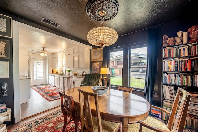 dining space featuring sink, a healthy amount of sunlight, and ceiling fan with notable chandelier