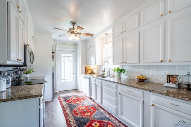 kitchen featuring light wood-type flooring, white cabinetry, dark stone countertops, and sink