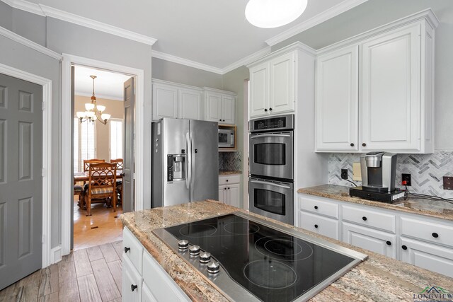 1303 Lesley, Longview, TX 75604 - kitchen with light wood-style flooring, appliances with stainless steel finishes, a chandelier, and white cabinetry