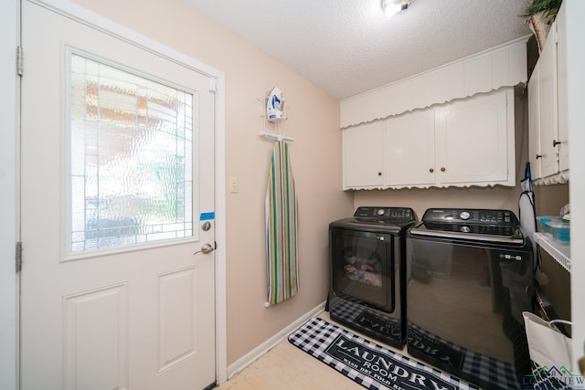 washroom with cabinets, a textured ceiling, washer and dryer, and a wealth of natural light