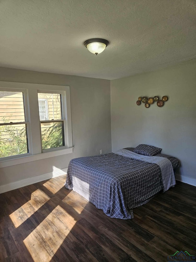 bedroom featuring dark hardwood / wood-style flooring and a textured ceiling