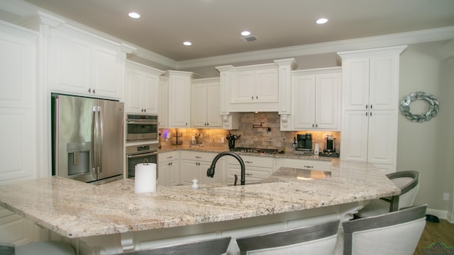 kitchen with white cabinets, a kitchen bar, sink, and appliances with stainless steel finishes