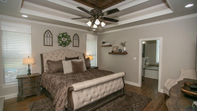 bedroom featuring dark hardwood / wood-style flooring, ensuite bathroom, ornamental molding, a raised ceiling, and ceiling fan