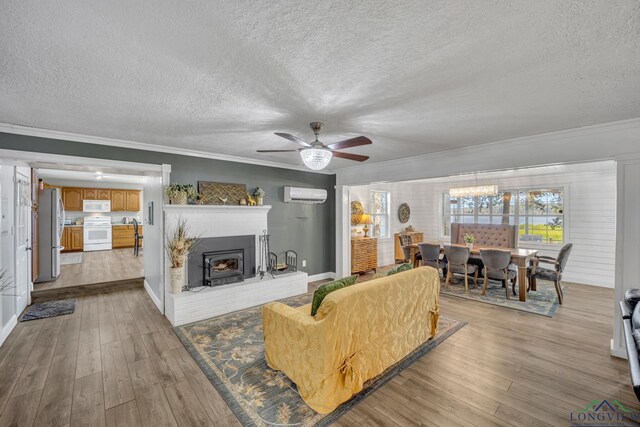 living room featuring hardwood / wood-style floors, ornamental molding, a wall mounted air conditioner, and ceiling fan