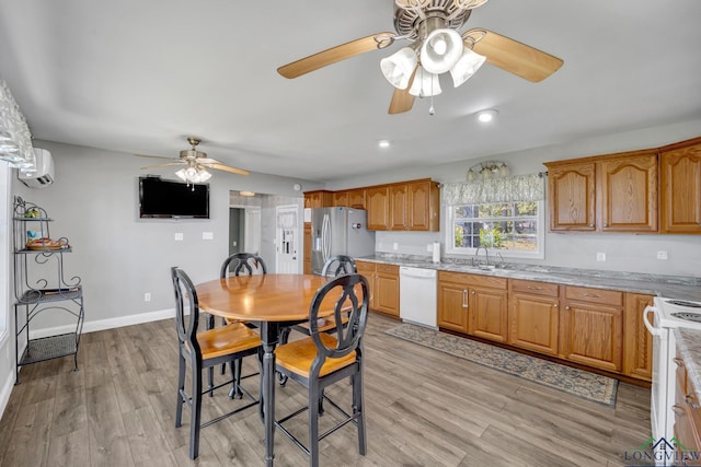 dining area with a wall unit AC, baseboards, light wood finished floors, and ceiling fan