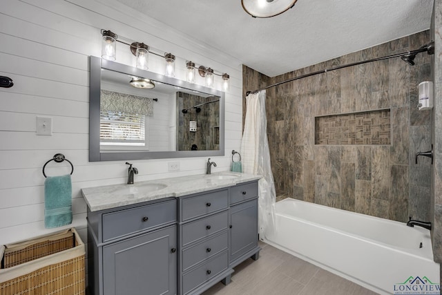 bathroom featuring a textured ceiling, double vanity, a sink, and shower / bath combo with shower curtain