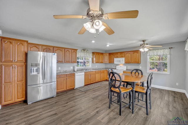 kitchen featuring light countertops, a sink, wood finished floors, and white appliances