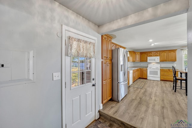 kitchen featuring light countertops, electric panel, light wood finished floors, and white appliances