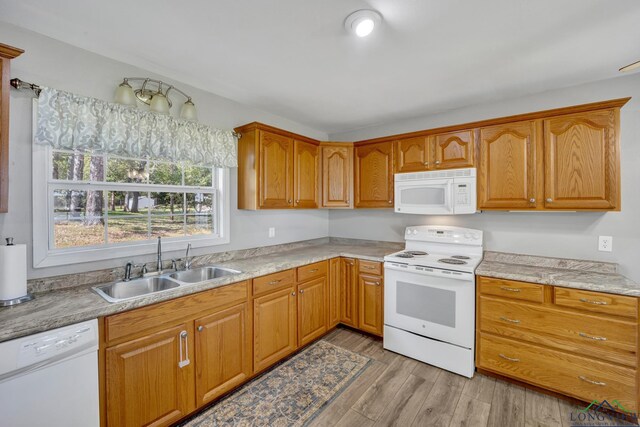 kitchen with white appliances, light wood-type flooring, light countertops, and a sink