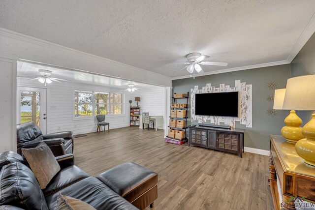 living area featuring a textured ceiling, crown molding, wood finished floors, and a ceiling fan