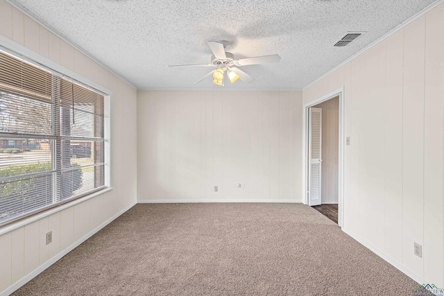 spare room featuring visible vents, ceiling fan, carpet, a textured ceiling, and crown molding