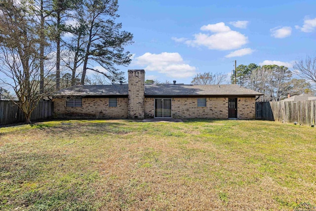 rear view of property featuring a fenced backyard, a lawn, and brick siding