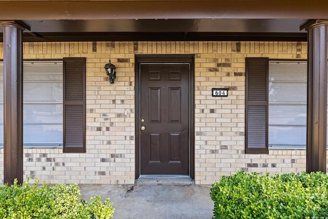 entrance to property with covered porch and brick siding