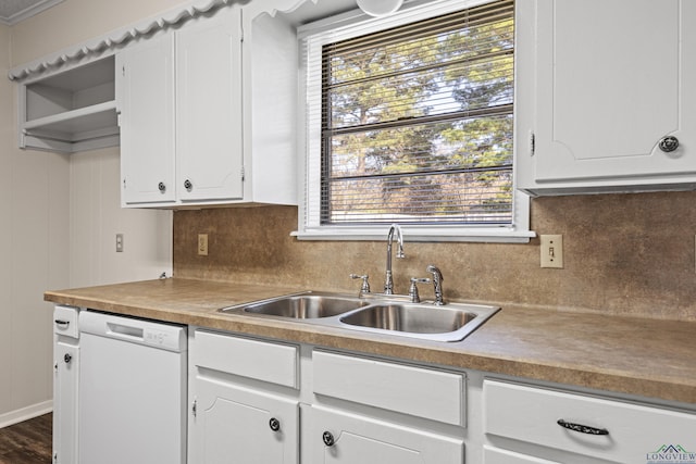 kitchen with white dishwasher, a sink, white cabinets, light countertops, and decorative backsplash