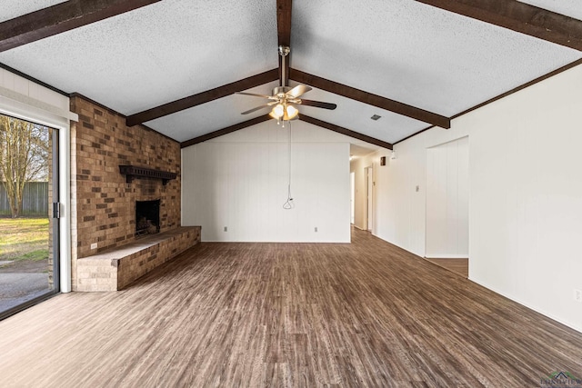 unfurnished living room with vaulted ceiling with beams, a fireplace, visible vents, a textured ceiling, and wood finished floors