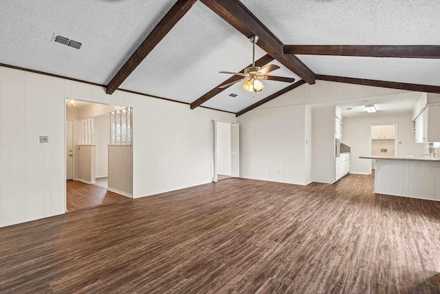 unfurnished living room featuring vaulted ceiling with beams, a textured ceiling, wood finished floors, and visible vents