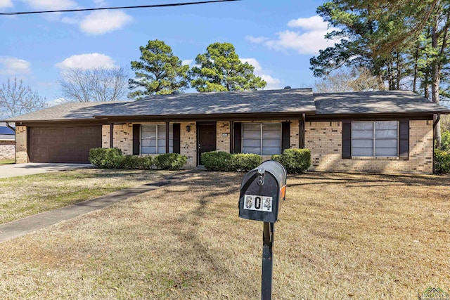 single story home featuring a front yard, concrete driveway, brick siding, and an attached garage