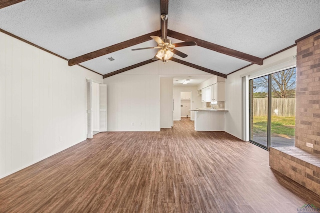 unfurnished living room featuring visible vents, lofted ceiling with beams, ceiling fan, wood finished floors, and a textured ceiling