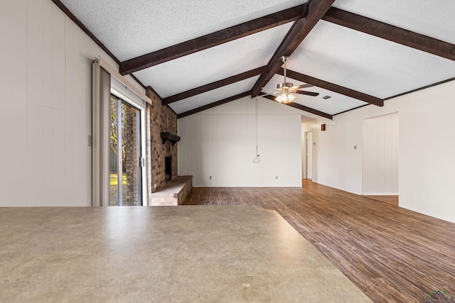 unfurnished living room featuring vaulted ceiling with beams, a ceiling fan, a brick fireplace, a textured ceiling, and wood finished floors