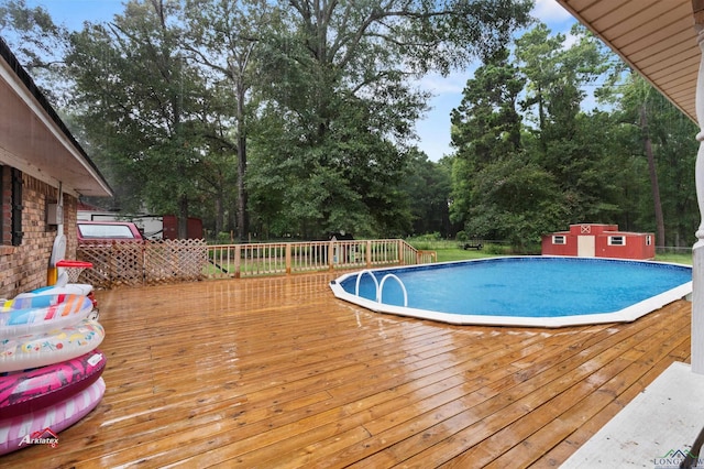 view of swimming pool featuring a storage unit and a deck