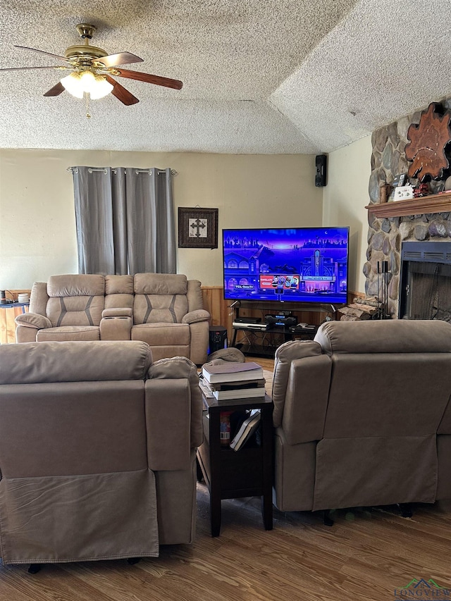 18335 Fm 1716 E, Tatum, TX 75691 - living room with ceiling fan, wood-type flooring, a stone fireplace, and a textured ceiling