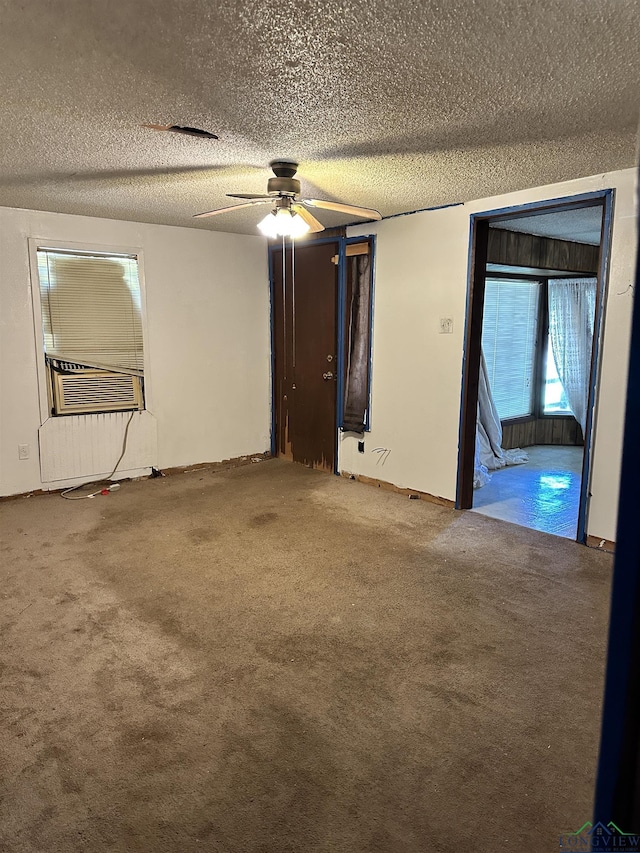 unfurnished room with a textured ceiling, carpet floors, and cooling unit