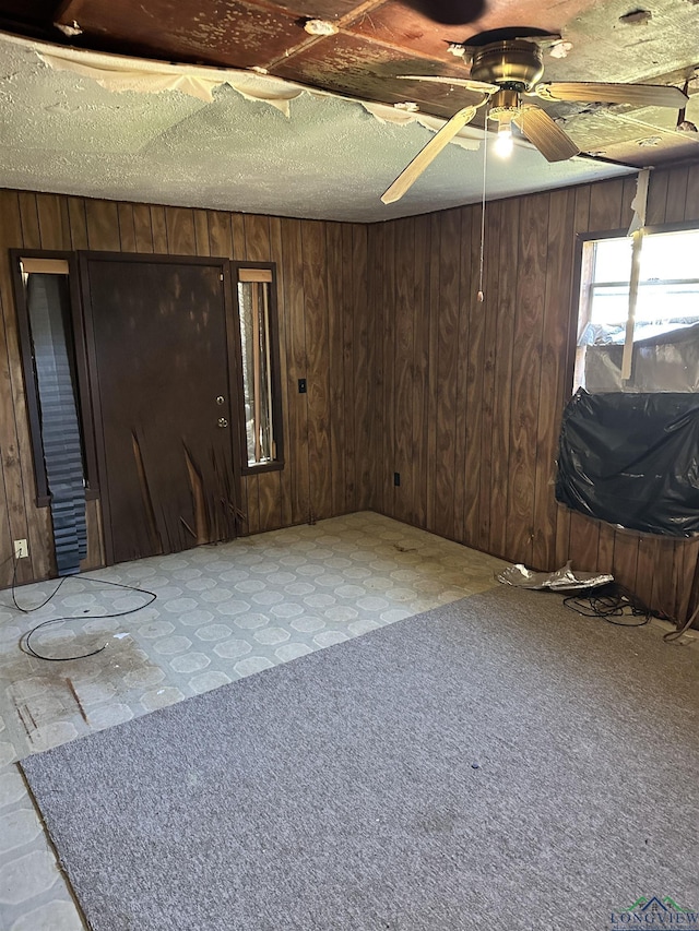 empty room featuring ceiling fan and wood walls