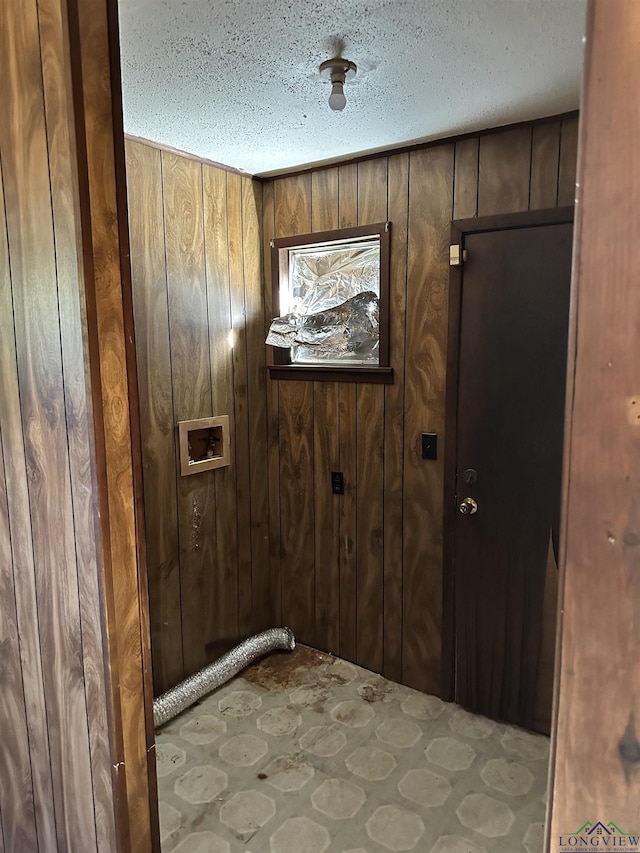 laundry room with washer hookup, a textured ceiling, and wood walls