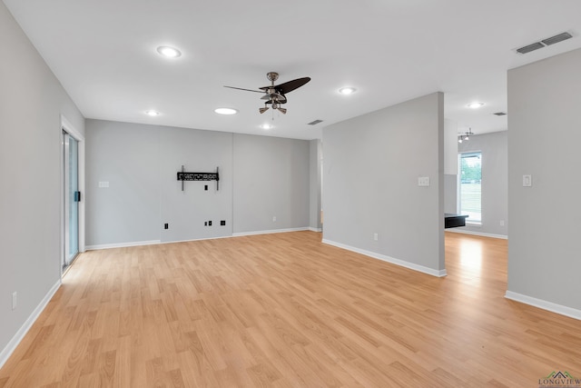 spare room with ceiling fan with notable chandelier and light hardwood / wood-style flooring