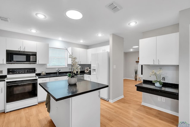 kitchen with white cabinetry, a center island, white appliances, and light hardwood / wood-style flooring