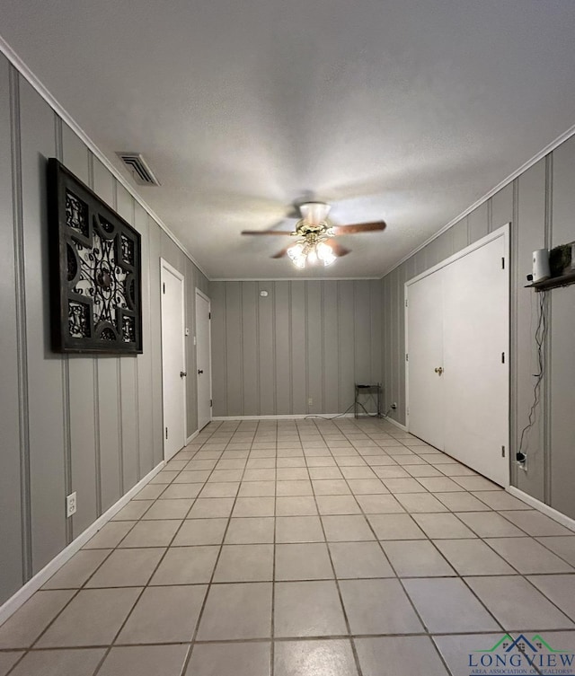 tiled spare room with ceiling fan and crown molding