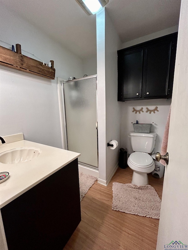 bathroom featuring vanity, hardwood / wood-style flooring, toilet, and a shower with shower door