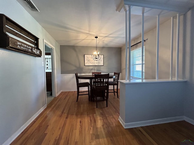 dining space with hardwood / wood-style floors and an inviting chandelier