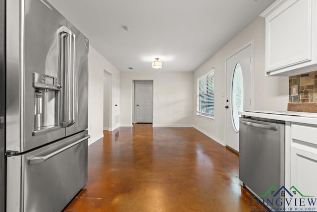 kitchen featuring white cabinets, stainless steel appliances, baseboards, and finished concrete floors